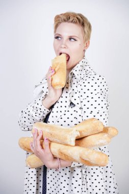 polka noktaları baget ile poz ve Studio beyaz bir arka plan üzerinde onları zevk ile bir bahar ceket kısa saçlı büyüleyici pinup kadın. artı retro giyim ekmek tutan boyutu kız.