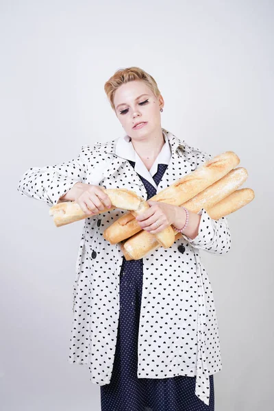 polka noktaları baget ile poz ve Studio beyaz bir arka plan üzerinde onları zevk ile bir bahar ceket kısa saçlı büyüleyici pinup kadın. artı retro giyim ekmek tutan boyutu kız.