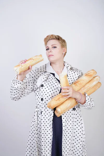 polka noktaları baget ile poz ve Studio beyaz bir arka plan üzerinde onları zevk ile bir bahar ceket kısa saçlı büyüleyici pinup kadın. artı retro giyim ekmek tutan boyutu kız.