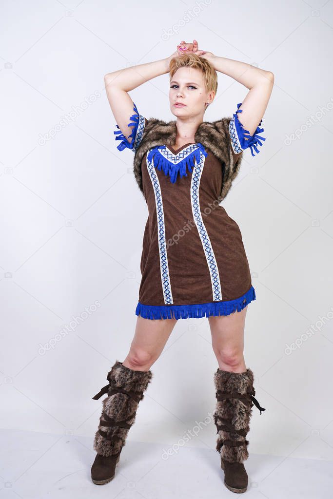 fashionable girl with short hair wearing primal style velvet dress and brown fur and posing on white studio background alone.