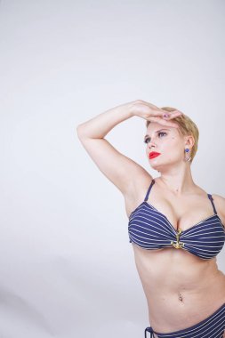 bir çizgili mayo büyük göğüsleri ile güzel Curvy beyaz kız stüdyo beyaz bir arka planda duruyor. çekici sarışın kız moda yaz iç çamaşırı tek başına poz.