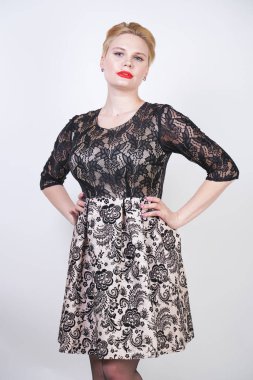 Sevimli tombul kız kısa modern şehir elbise beyaz kumaş ve siyah dantel yapılmış beyaz arka planda seksi çorap poz stüdyo