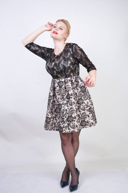 Sevimli tombul kız kısa modern şehir elbise beyaz kumaş ve siyah dantel yapılmış beyaz arka planda seksi çorap poz stüdyo