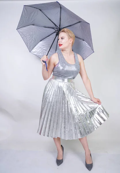 cute chubby short hair girl in a modern city metallic silver dress holding an umbrella and posing on a white background in the Studio alone
