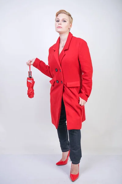 cute short hair chubby girl in a modern city wool coat holding a red umbrella and posing on a white background in the Studio alone