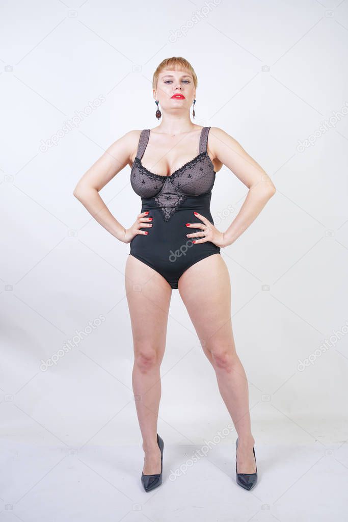 pretty short hair blonde woman with plus size body wearing retro black lingerie and posing on white studio background alone
