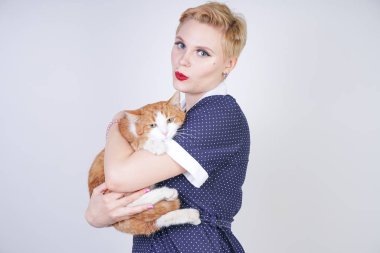 Pinup Polka kısa saçlı sevimli tür kadın stüdyo beyaz bir arka planda onu sevgili Pet tutan elbise nokta. artı boyutu yetişkin sarışın kız ve turuncu kedi birlikte mutlu.
