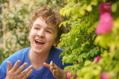 Genç adam çiçekler arasında duruyor ve yaz ve çiçekli sahiptir