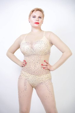 bej iç çamaşırı seksi Curvy kız ve stüdyo beyaz arka planda poz Rhinestones tüm vücut için şeffaf tulum. Erotik dans kostümü kısa saçlı şık genç kadın.