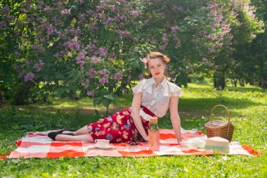 doğaya dinlenmiş olan kız oldukça genç pin. tartan ekose oturan vintage elbise giyen mutlu ince genç kadın ve yalnız yaz günü rahatlatıcı.