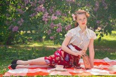 doğaya dinlenmiş olan kız oldukça genç pin. tartan ekose oturan vintage elbise giyen mutlu ince genç kadın ve yalnız yaz günü rahatlatıcı.