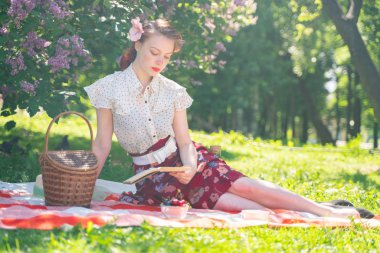 doğaya dinlenmiş olan kız oldukça genç pin. tartan ekose oturan vintage elbise giyen mutlu ince genç kadın ve yalnız yaz günü rahatlatıcı.