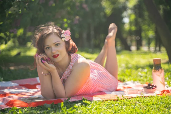 魅力的なピンナップの女の子は 緑の夏の草の上に休息とピクニックを楽しんでいます かなりヴィンテージスタイルの白人女性は 単独で都市公園に空き地を過ごす — ストック写真