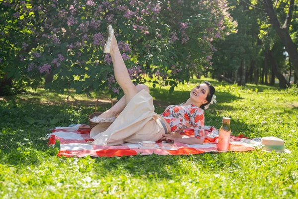 魅力的なブルネットの若い女の子は 一人で緑の夏の草の上に休息とピクニックを楽しんでいます かわいい女性は休日を持っており 自然に空き地を過ごす — ストック写真