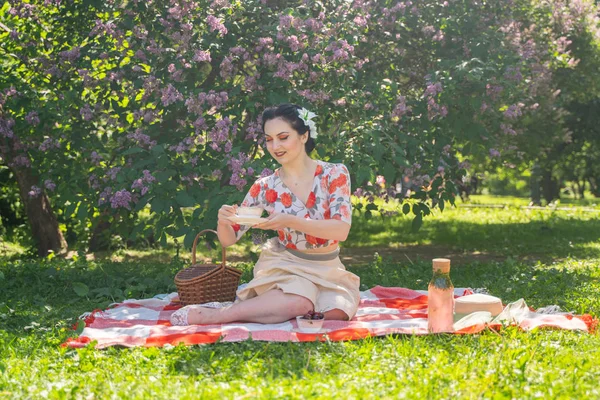 魅力的なブルネットの若い女の子は 一人で緑の夏の草の上に休息とピクニックを楽しんでいます かわいい女性は休日を持っており 自然に空き地を過ごす — ストック写真