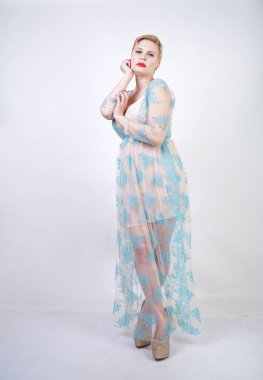 kısa saçlı ve artı boyutu vücut uzun şeffaf mavi dantel elbise giyen oldukça sevimli sarışın kadın. beyaz stüdyo arka plan tek başına sevimli gecelik şık şık yetişkin kız.