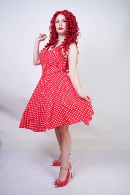 artı boyutu kırmızı saç kıvırcık kadın kıvrımlı vücut retro polka nokta güzel elbise giyen ve beyaz stüdyo arka plan tek başına ayakta. vintage giysiler poz tombul eğlenceli moda kız.
