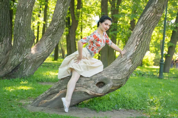 緑の夏の庭で彼女の美しい木と一緒にポーズかなりかわいい若いブルネットの女性 自然の中で幸せな女の子の喜び 市内の公園と休息に楽しみを持って — ストック写真