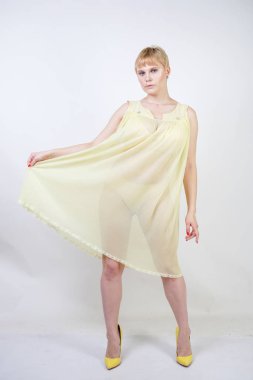 kısa saçlı ve tombul vücut şeffaf gecelik giyen ve beyaz stüdyo arka plan tek başına poz ile güzel genç kadın. sarı pilili iç çamaşırı elbise ayakta güzel sarışın artı boyutu kız.