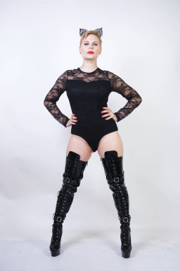 beyaz stüdyo arka plan üzerinde poz kısa sarı saçlı güzel artı boyutu genç kadın. siyah dantel bodysuit sıcak tombul moda kız ve patent deri uyluk yüksek çizmeler kedi kadın tek başına ayakta.
