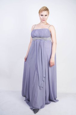 gri uzun elbise zarif kalın kadın. beyaz stüdyo arka plan üzerinde duran gece elbisesi güzel artı boyutu kadın. gri giysiler içinde kısa saç tombul kız tek başına poz.