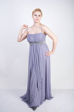 gri uzun elbise zarif kalın kadın. beyaz stüdyo arka plan üzerinde duran gece elbisesi güzel artı boyutu kadın. gri giysiler içinde kısa saç tombul kız tek başına poz.