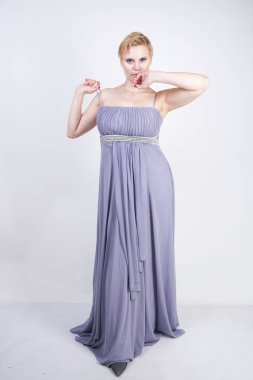 gri uzun elbise zarif kalın kadın. beyaz stüdyo arka plan üzerinde duran gece elbisesi güzel artı boyutu kadın. gri giysiler içinde kısa saç tombul kız tek başına poz.