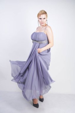 gri uzun elbise zarif kalın kadın. beyaz stüdyo arka plan üzerinde duran gece elbisesi güzel artı boyutu kadın. gri giysiler içinde kısa saç tombul kız tek başına poz.