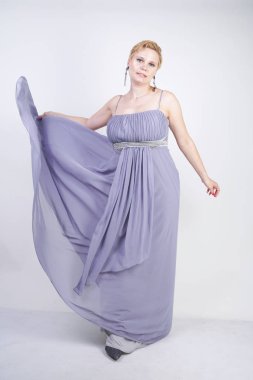 gri uzun elbise zarif kalın kadın. beyaz stüdyo arka plan üzerinde duran gece elbisesi güzel artı boyutu kadın. gri giysiler içinde kısa saç tombul kız tek başına poz.