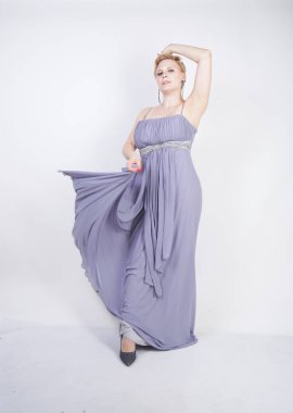 gri uzun elbise zarif kalın kadın. beyaz stüdyo arka plan üzerinde duran gece elbisesi güzel artı boyutu kadın. gri giysiler içinde kısa saç tombul kız tek başına poz.