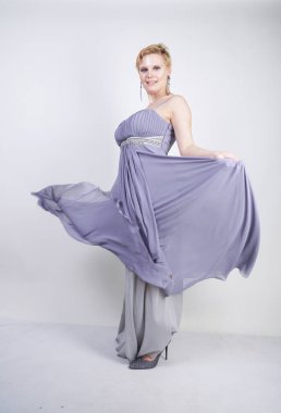 gri uzun elbise zarif kalın kadın. beyaz stüdyo arka plan üzerinde duran gece elbisesi güzel artı boyutu kadın. gri giysiler içinde kısa saç tombul kız tek başına poz.