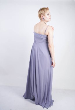 gri uzun elbise zarif kalın kadın. beyaz stüdyo arka plan üzerinde duran gece elbisesi güzel artı boyutu kadın. gri giysiler içinde kısa saç tombul kız tek başına poz.