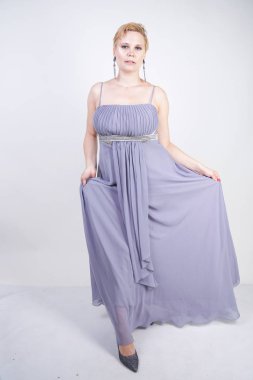 gri uzun elbise zarif kalın kadın. beyaz stüdyo arka plan üzerinde duran gece elbisesi güzel artı boyutu kadın. gri giysiler içinde kısa saç tombul kız tek başına poz.