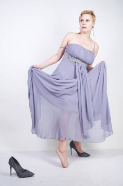 büyüleyici artı gri elbise elbiseli genç kadın Studio beyaz arka planda terlik kaybetti. gece kıyafetleri ve yüksek topuk ayakkabı yakın duran güzel tombul kısa saç sarışın kız.