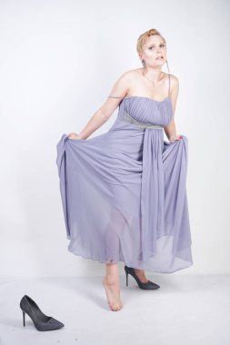 gri uzun elbise zarif kalın kadın. beyaz stüdyo arka plan üzerinde duran gece elbisesi güzel artı boyutu kadın. gri giysiler içinde kısa saç tombul kız tek başına poz.