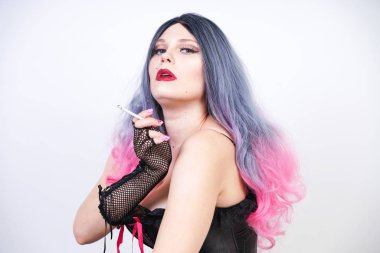 siyah korse piercing ve uzun gri pembe saç ve örgü eldiven ile yırtık file külotlu çorap ile kötü kız katta oturan ve Studio tek başına beyaz arka plan üzerinde sigara sigara