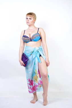 kıvrımlı rakam ile sevimli kız Studio beyaz arka plan üzerinde pareo ile fuşya pembe şapka ve mavi mayo duruyor. tek başına poz moda beachwear güzel kıvrımlı tombul kadın.