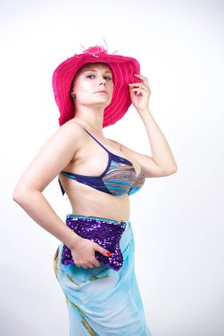 kıvrımlı rakam ile sevimli kız Studio beyaz arka plan üzerinde pareo ile fuşya pembe şapka ve mavi mayo duruyor. tek başına poz moda beachwear güzel kıvrımlı tombul kadın.