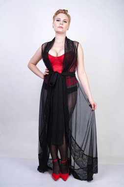 güzel şık artı kırmızı dantel korse kısa saçlı ve siyah sırf uzun bornoz ile sarışın, tek başına beyaz arka plan üzerinde poz çelik topuk ile dikiş ve kırmızı patent deri ayakkabı ile seksi külotlu çorap