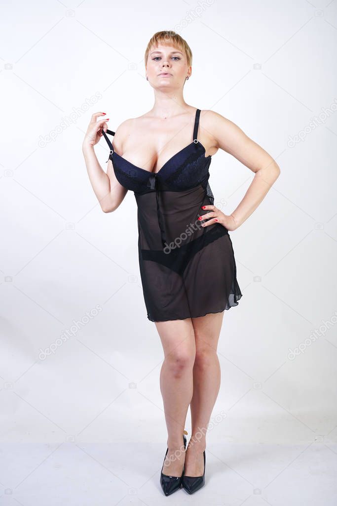 plus size adult girl wearing transparent underwear dress. beautiful chubby woman in black lingerie posing alone on white studio background. pretty sexual female with blonde short hair and curvy body.