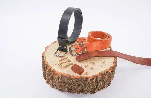 man makes by hands leather belt with buckle. handmade hobby. young man resting by manufacture his designer belts. man with a screwdriver in his hands twists rivets close up on white studio background.