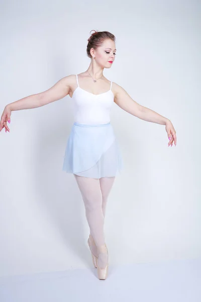 バレエ服を着たかわいい白人の女の子は スタジオで白い背景にバレリーナであることを学びます プラスサイズの若い女性はダンサーになることを夢見る — ストック写真