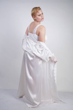 dantel zarif bornoz güzel kıvrımlı kafkas kız. kısa saçlı büyüleyici tombul kadın ve artı boyutu rakam Studio beyaz arka plan üzerinde gelin bodysuit ve uzun elbise duruyor.