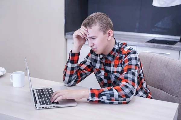 Грустный Молодой Человек Клетчатой Рубашке Сидит Столом Перед Ноутбуком Один — стоковое фото
