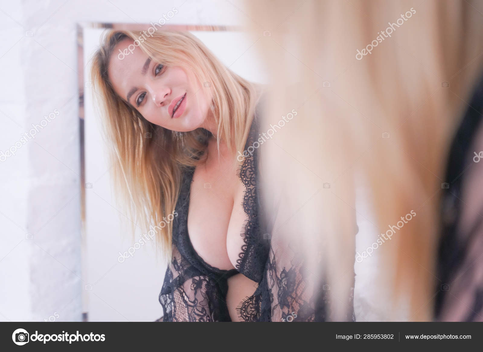 Charming plus size caucasian blonde woman dressed in beautiful lace black lingerie and looking at herself in the mirror at home alone Stock Photo by ©agnadevi 285953802