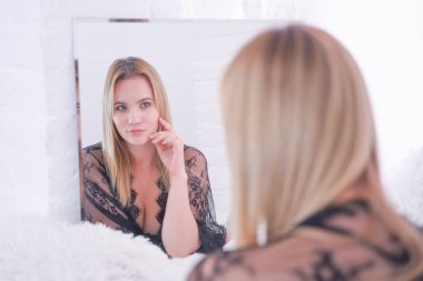 güzel dantel siyah iç çamaşırı giymiş büyüleyici artı boyutu kafkas sarışın kadın ve evde tek başına aynada kendine bakıyor