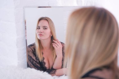 güzel dantel siyah iç çamaşırı giymiş büyüleyici artı boyutu kafkas sarışın kadın ve evde tek başına aynada kendine bakıyor