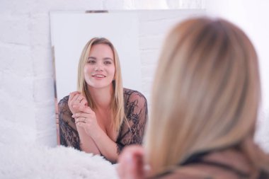 güzel dantel siyah iç çamaşırı giymiş büyüleyici artı boyutu kafkas sarışın kadın ve evde tek başına aynada kendine bakıyor