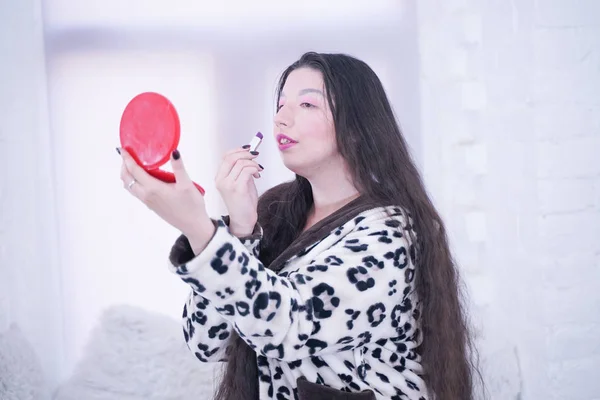 Woman applying lipstick looking at mirror in hand. Hot lips makeup closeup at home. — Stock Photo, Image