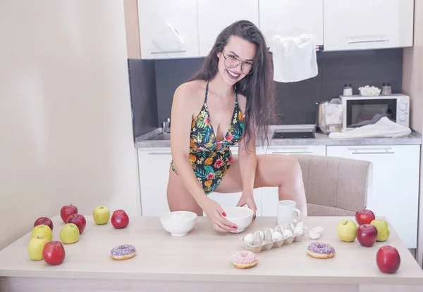 Mujer feliz en traje de baño de moda con hojas verdes posando en cocina blanca —  Fotos de Stock